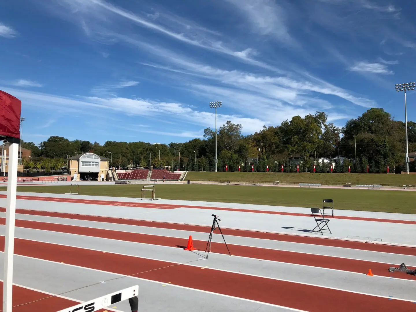 Athletic track with hurdles set up under a blue sky and scattered clouds.