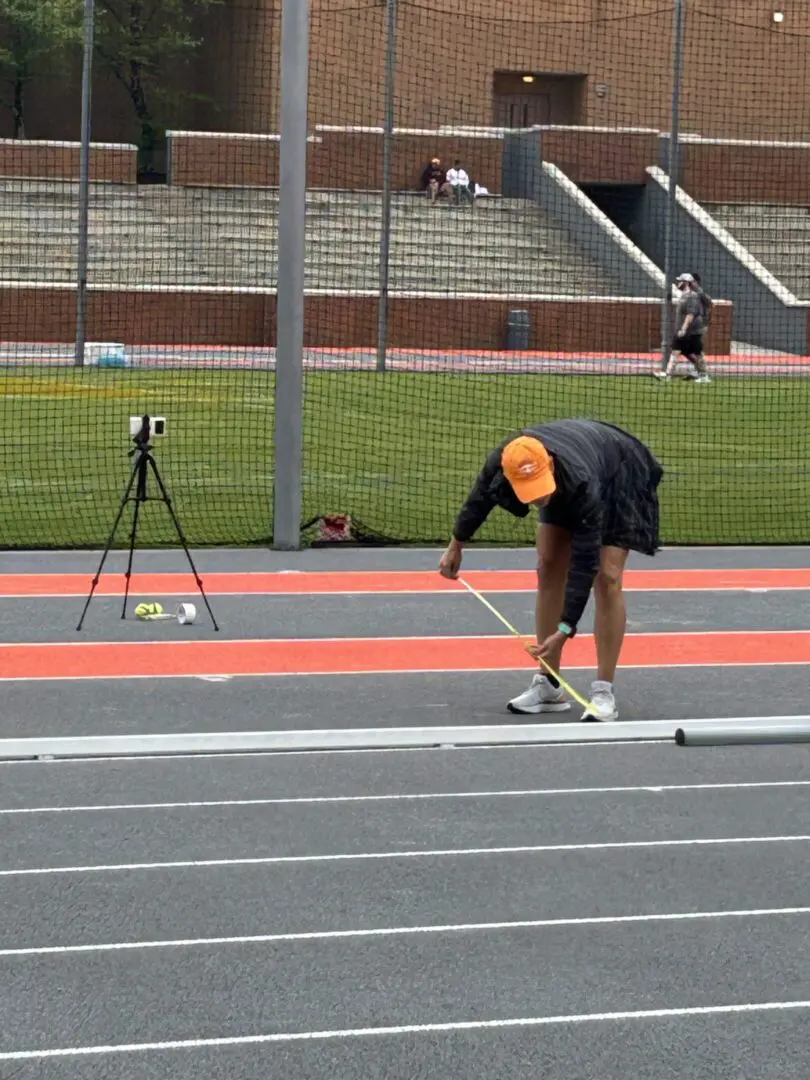 Person setting up equipment on a track field.